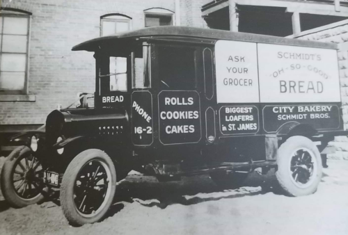 Black and white photo of an old delivery truck advertising Schmidt's bread, rolls, cookies, and cakes.