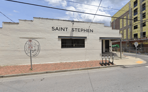 Exterior of a building labeled "Saint Stephen," with scooters parked outside and construction in the background.