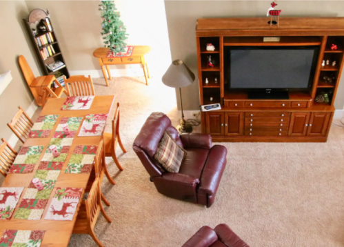 A cozy living room with a wooden dining table, a TV unit, and a Christmas tree in the corner.