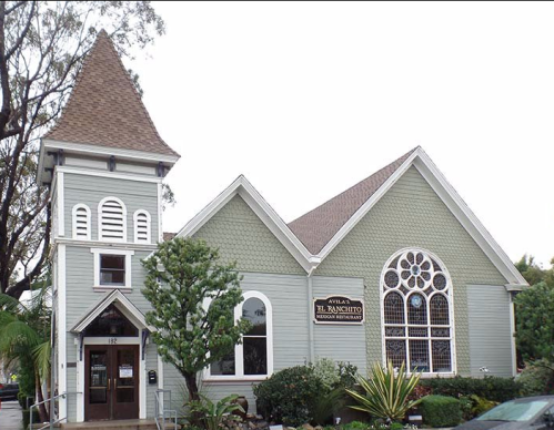 A charming green building with a tall spire, featuring decorative windows and a sign for "El Nanchito Mexican Restaurant."