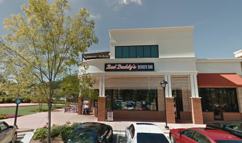 Exterior of Bad Daddy's Burger Bar, a casual dining restaurant, with a clear blue sky and trees in the foreground.