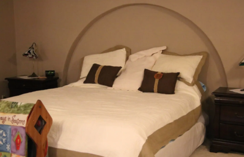 A cozy bedroom featuring a neatly made bed with decorative pillows and wooden nightstands on either side.