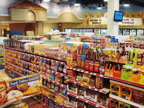 A grocery store aisle filled with various food products and snacks, with signs welcoming customers to Russell's.