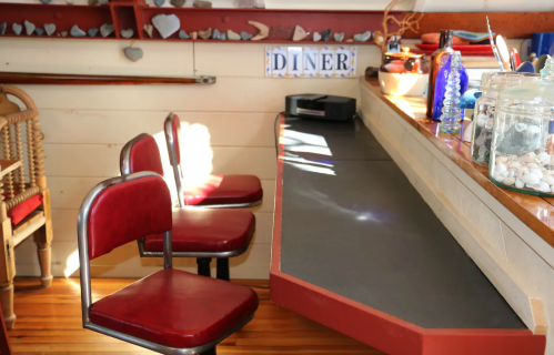 A cozy diner interior with two red chairs and a counter adorned with decorative items and jars.