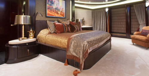 Luxurious bedroom featuring a large bed with decorative pillows, elegant lighting, and rich wood accents.