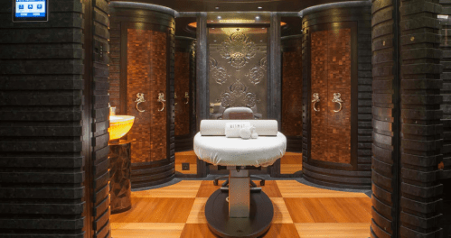 A luxurious spa treatment room with a massage table, elegant decor, and warm lighting.
