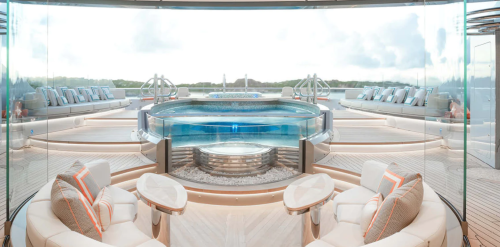 Luxurious yacht interior featuring a glass-enclosed pool, elegant seating, and panoramic views of the water.