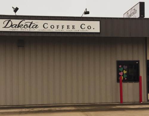 Exterior of Dakota Coffee Co. building with a sign and a window decorated with colorful hearts.