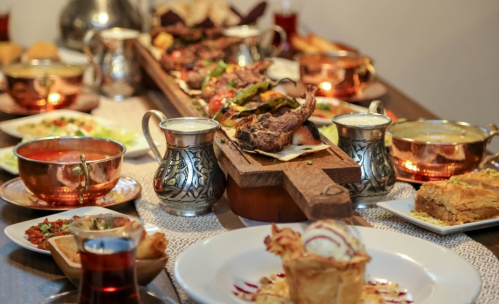 A beautifully arranged table with various dishes, including roasted meat, salads, desserts, and drinks in decorative bowls.
