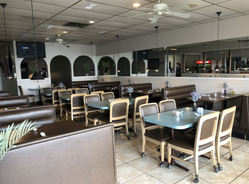 Interior of a restaurant featuring brown booths, blue tables, and a mirrored wall, with a casual and inviting atmosphere.