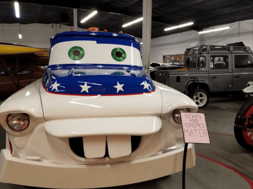 A cartoonish truck with a blue and white star-patterned design, smiling, next to a sign that reads "STARS AND STRIPES MATTER."