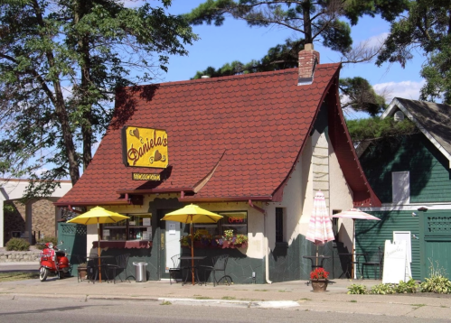 A quaint restaurant with a red-tiled roof, yellow umbrellas, and a sign reading "Daniel's" on a sunny day.