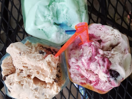 Three bowls of colorful ice cream: mint green, pink with swirls, and brown with chocolate chips, each with a straw.