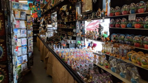 A colorful shop aisle filled with various trinkets, figurines, and souvenirs on display along both sides.