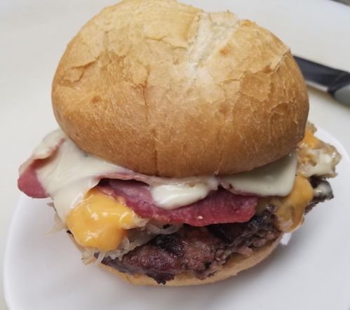 A close-up of a hearty sandwich with layers of meat, cheese, and mayonnaise, served on a soft bun.