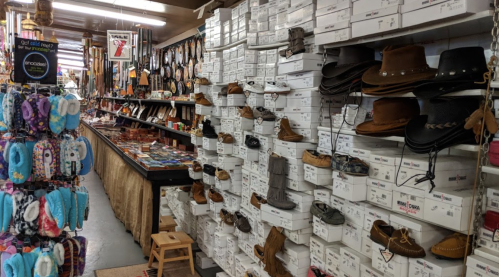 A cozy store interior filled with stacked shoe boxes, various footwear, and accessories displayed on walls and shelves.