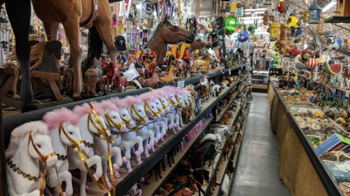 A colorful display of toy horses and various collectibles on shelves in a vibrant store aisle.