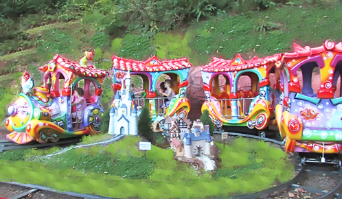 Colorful children's train ride with kids enjoying the attractions in a vibrant outdoor setting.