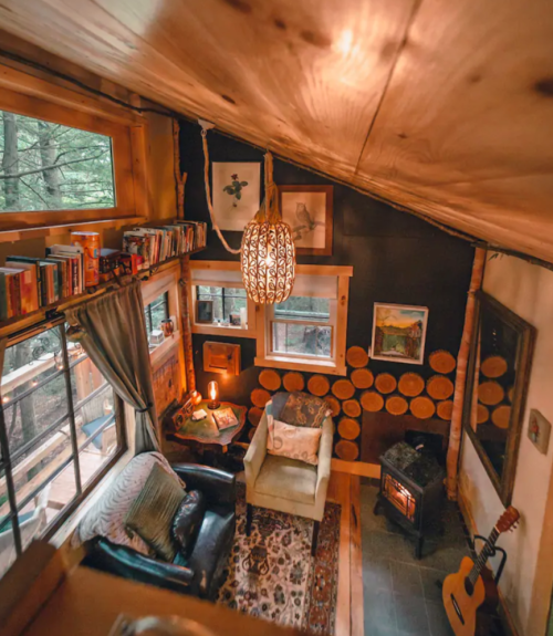 Cozy cabin interior with a warm atmosphere, featuring a fireplace, bookshelves, and rustic decor.