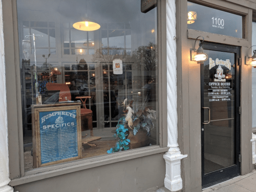 A storefront window displaying a sign for "Humphrey's Specifics" and decorative items inside.