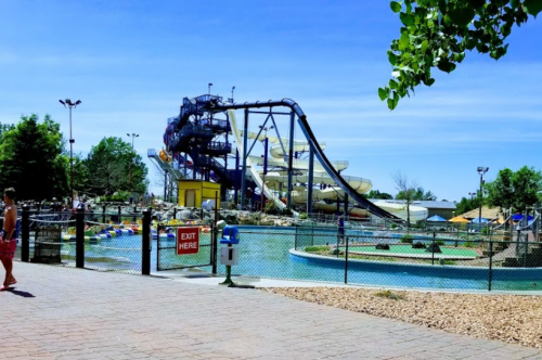 A water park featuring large slides, a lazy river, and a mini-golf area under a clear blue sky.