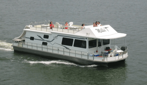 A white houseboat with people on the upper deck cruising on calm water.