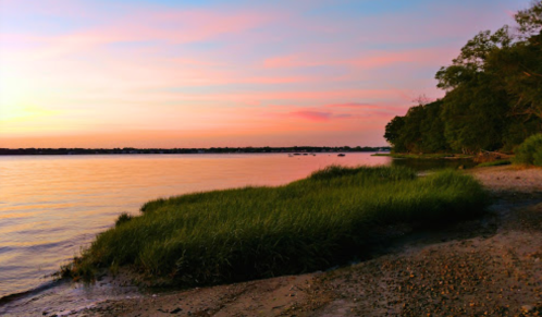 A serene lakeside view at sunset, with colorful skies reflecting on the water and lush greenery along the shore.