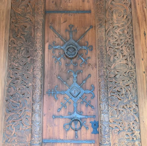 Intricately carved wooden door with ornate metal hardware and decorative patterns.