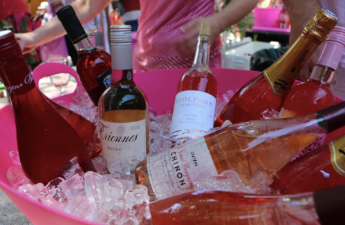 A pink bucket filled with ice and various bottles of rosé wine.