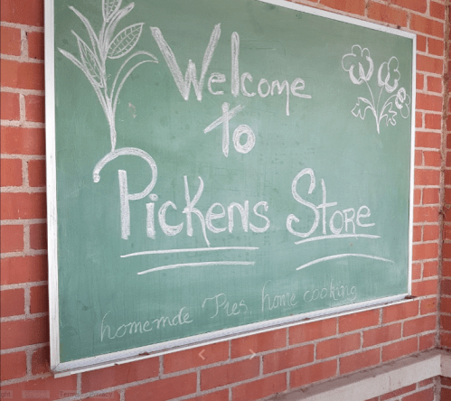 Chalkboard sign welcoming visitors to Pickens Store, featuring homemade pies and home cooking.