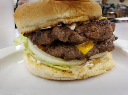 A close-up of a double cheeseburger with lettuce, onion, and mayonnaise on a toasted bun.