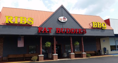 Exterior of "Fat Buddies BBQ" restaurant featuring a red and yellow sign, with "Ribs" and "BBQ" prominently displayed.