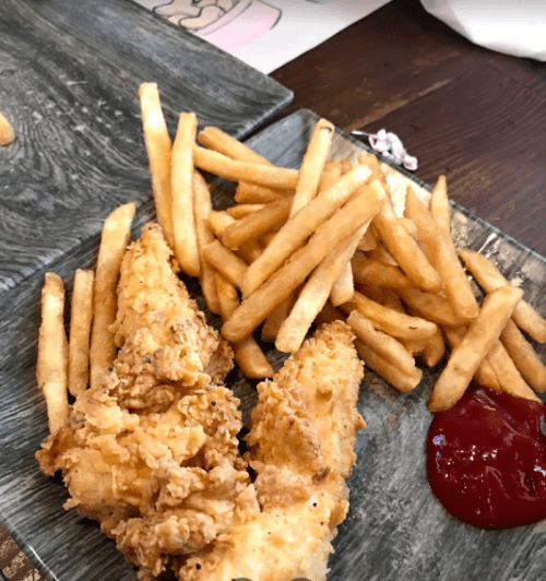 A plate with two pieces of fried chicken, a serving of golden fries, and a small portion of ketchup.