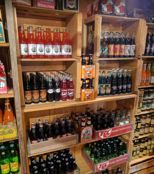 Shelves filled with various colorful soda bottles, including vintage and craft brands, in a store display.