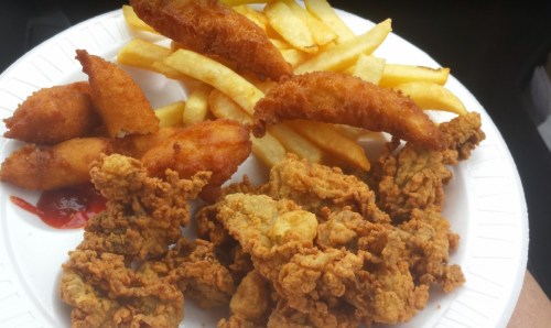 A plate of fried chicken, golden fries, and crispy fried snacks with a side of ketchup.