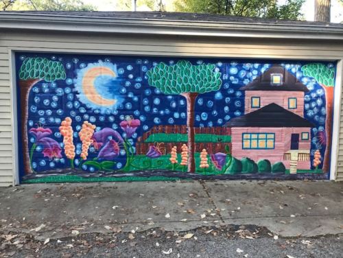 Colorful mural on a garage depicting a house, trees, flowers, and a night sky with a crescent moon.