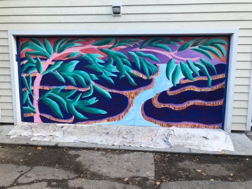 Colorful mural on a garage door featuring abstract trees and a winding river against a vibrant background.