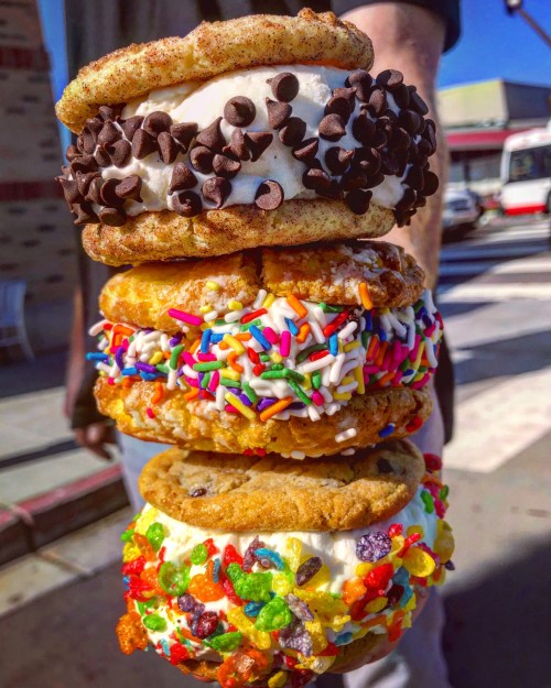 A stack of four colorful ice cream sandwiches made with various cookies and toppings, including chocolate chips and sprinkles.