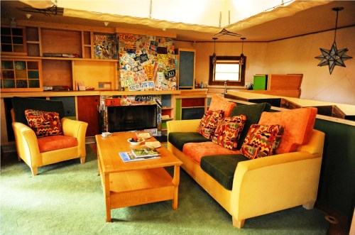 Cozy living room with colorful furniture, a wooden coffee table, and a unique wall decorated with license plates.