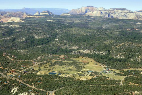 Aerial view of a lush green valley surrounded by rugged mountains and plateaus under a clear blue sky.