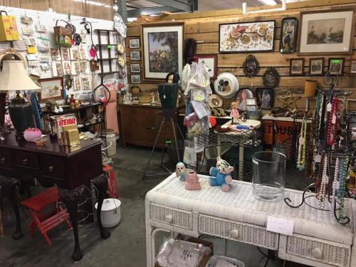 A vintage shop filled with various antiques, including furniture, decor, and jewelry displayed on tables and walls.