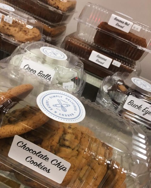 A display of assorted baked goods in clear containers, including chocolate chip cookies, Oreo balls, and banana bread.