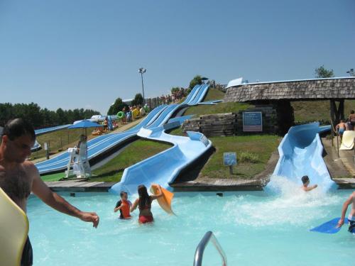 A water park scene with multiple slides, people swimming, and enjoying the sun on a clear day.