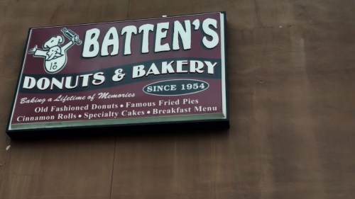 Sign for Batten's Donuts & Bakery, established in 1954, featuring donuts, fried pies, and specialty cakes.