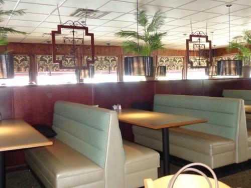 Interior of a restaurant featuring green booths, wooden accents, and hanging light fixtures with plants.