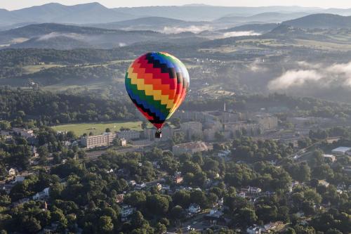A colorful hot air balloon floats above a scenic landscape with mountains and a town below.