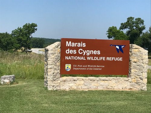 Sign for Marais des Cygnes National Wildlife Refuge, featuring a brown background and blue bird graphics.
