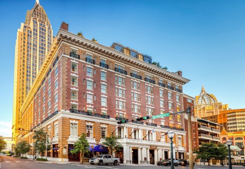 Historic brick hotel building with modern skyscraper in the background, bathed in warm sunset light.