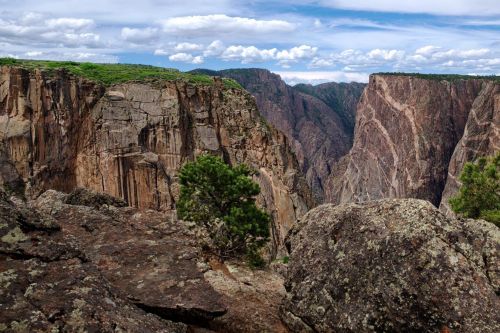 A stunning view of steep canyon walls and rocky cliffs under a blue sky with scattered clouds.