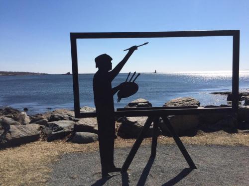 A silhouette of a painter holding a brush and palette, framed by a large picture frame overlooking the ocean.